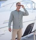 Model by a boat wearing Coast Apparel Bowman Button Down Shirt olive